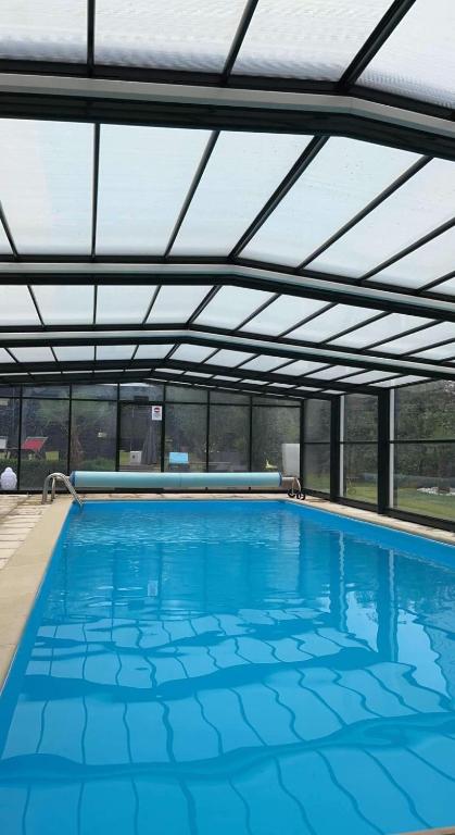 une grande piscine avec un toit dans l'établissement Évasion du préhaut, à Tournehem