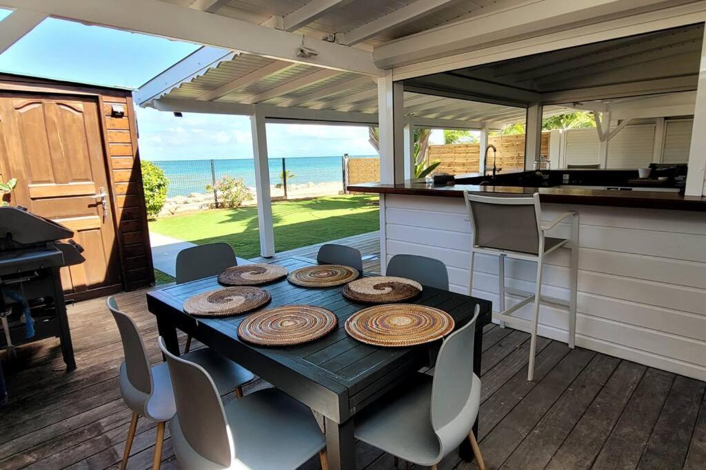 a table and chairs in a kitchen with the ocean at Maison bord de mer in Le Gosier