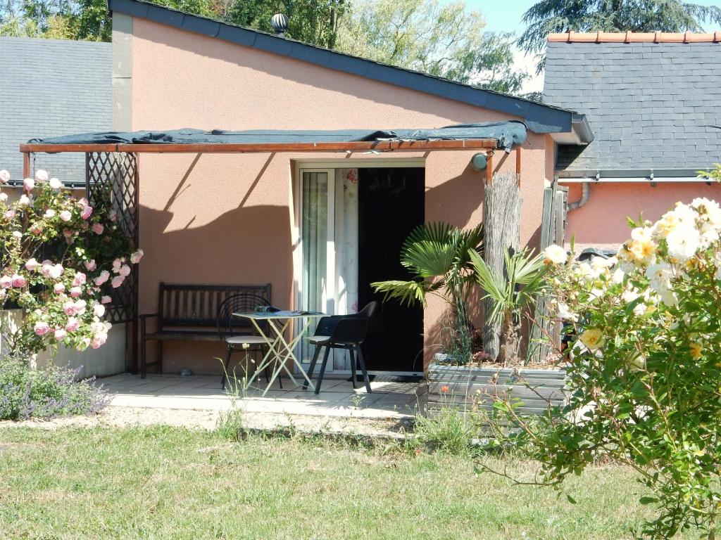 una casa rosa con un tavolo e un patio di Gîte à la campagne proche d'Angers et de la Loire a Saint-Martin-du-Fouilloux