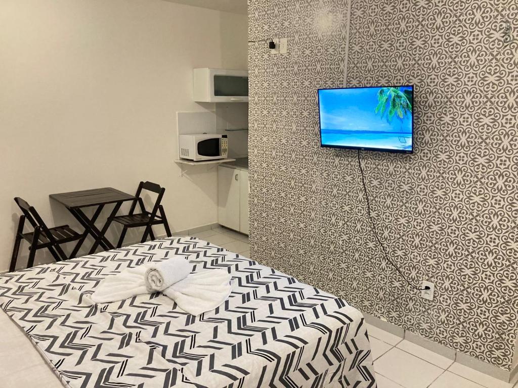 ジョアンペソアにあるJr FLATSの壁にテレビとベッドが備わる客室です。