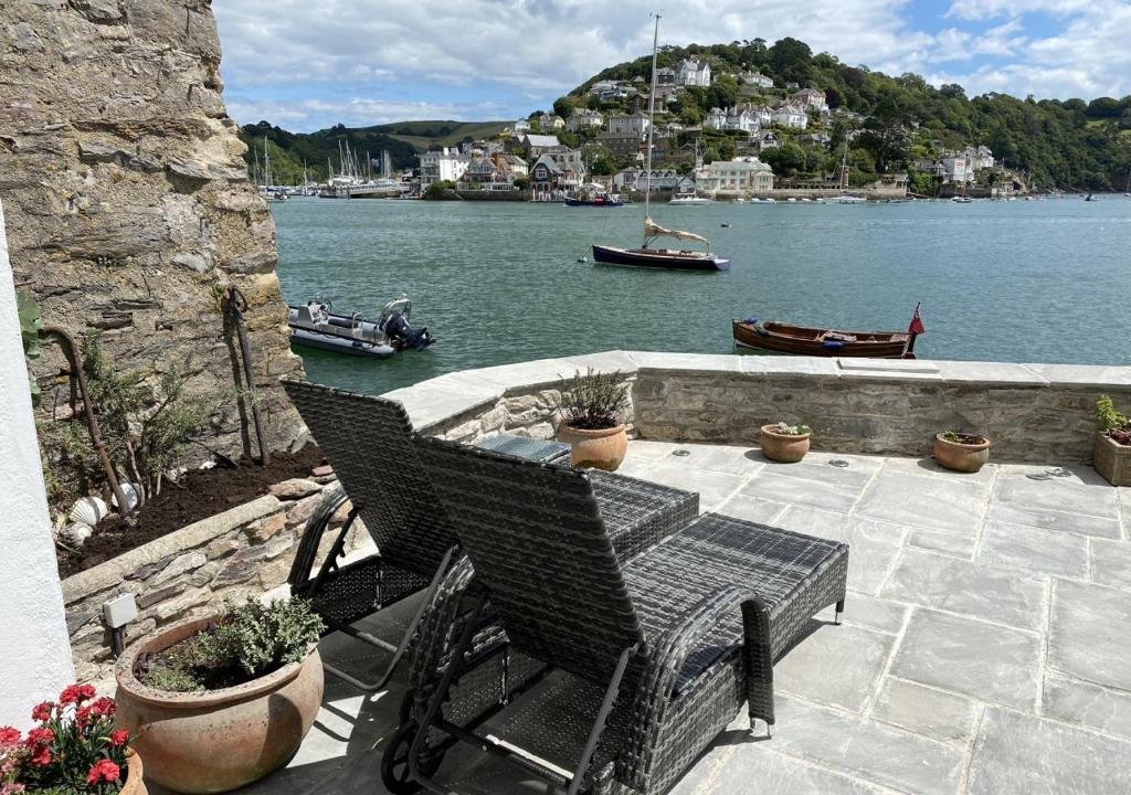a patio with two chairs and a view of the water at Gullsway Lower in Dartmouth