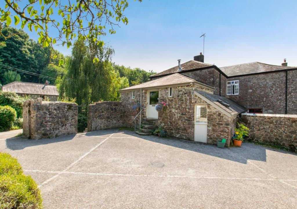a stone house with a driveway and a garage at Bovey Cottage in Broadhempston