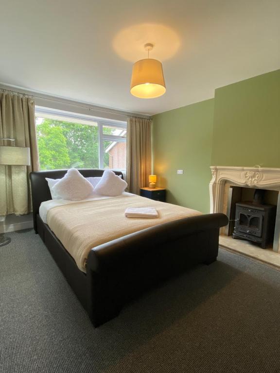 a bedroom with a large bed and a fireplace at Spacious 4 Bedroom House in Northampton by HP Accommodation - Free Private Parking in Northampton