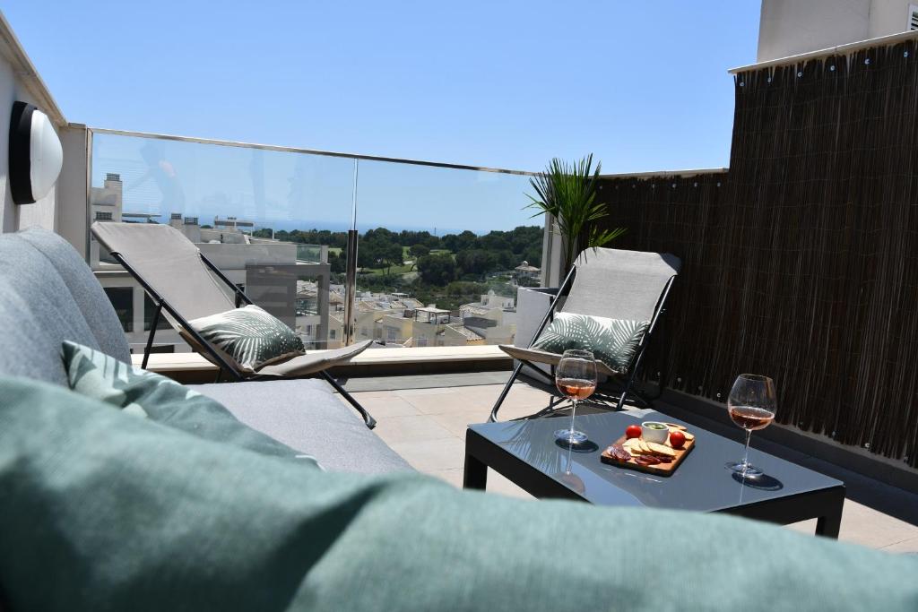 2 Gläser Wein und ein Tablett mit Essen auf dem Balkon in der Unterkunft Luxurious flat & private rooftop in Villamartin Orihuela Costa in Orihuela