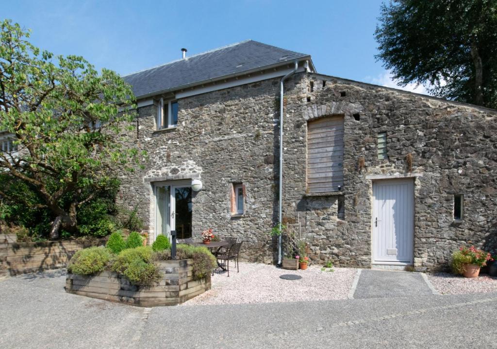 an old stone house with a white door at Teign Cottage in Broadhempston