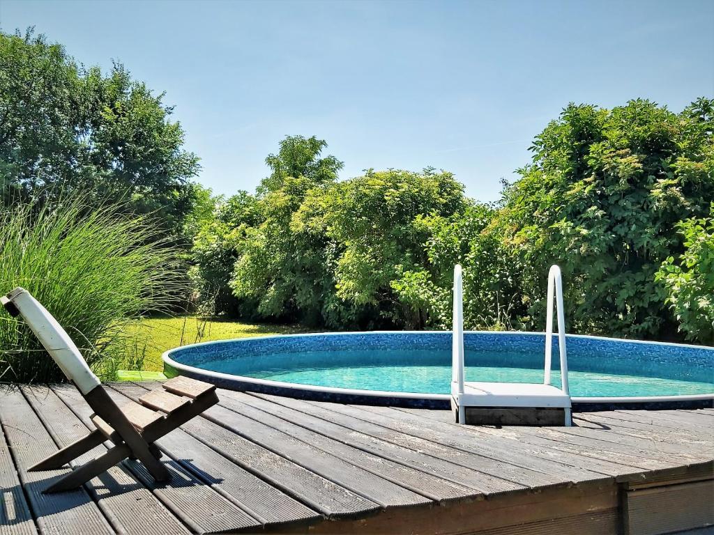 een zwembad met twee stoelen op een houten terras bij KultúrÉlet Vendégháza in Kétegyháza