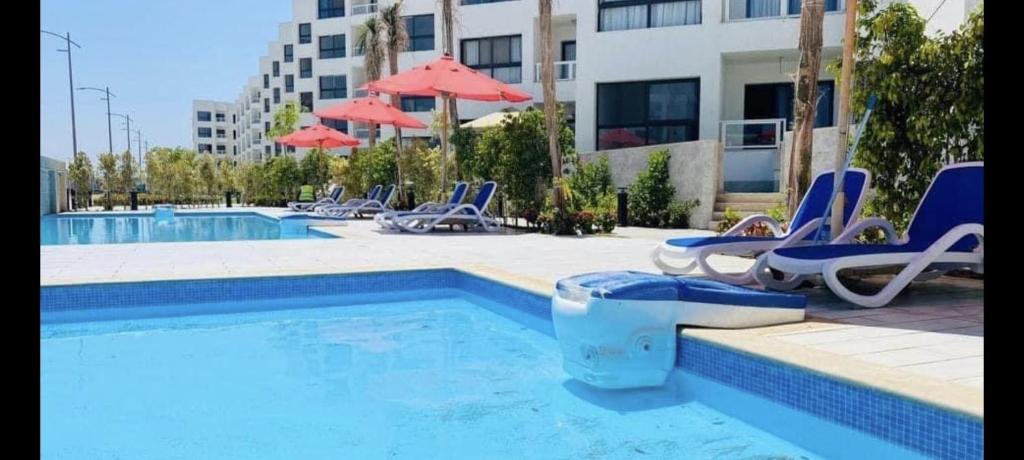 einen Pool mit Stühlen und Sonnenschirmen neben einem Gebäude in der Unterkunft Porto Said Tourist Resort Luxury Hotel Apartment in Port Said