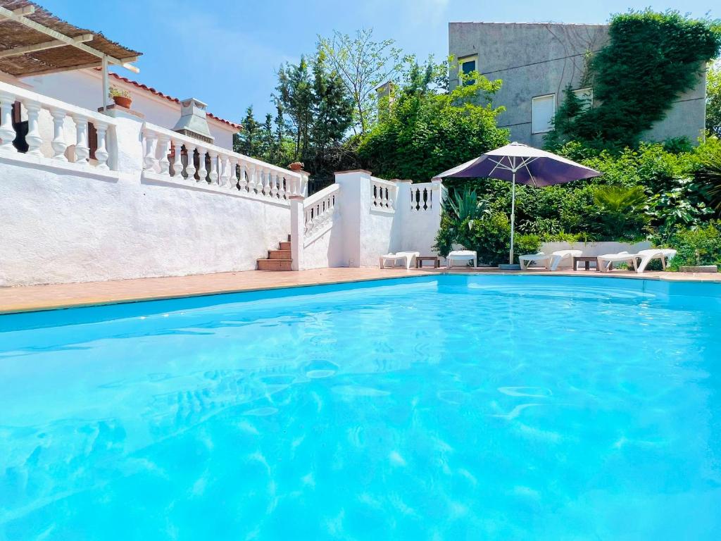 - une piscine dans une maison avec un parasol dans l'établissement Villa Mas Blau Munt, à Lloret de Mar