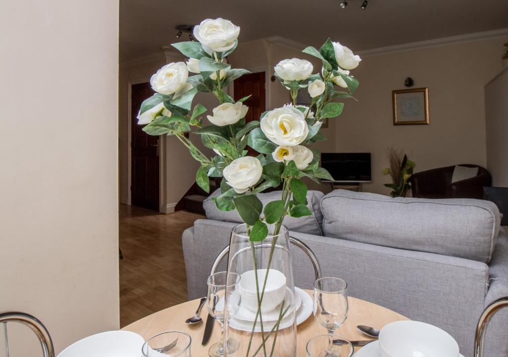 a vase filled with white roses sitting on a table at Sunnyhill Mews in Torquay