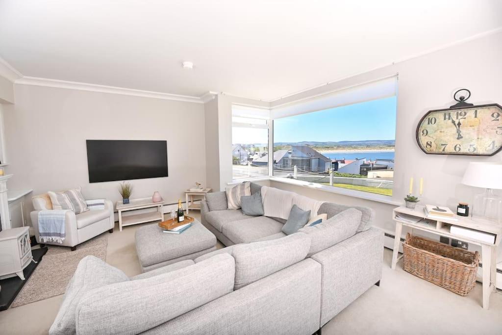 a living room with a couch and a large window at Strandene (63 Strand Road) in Portstewart