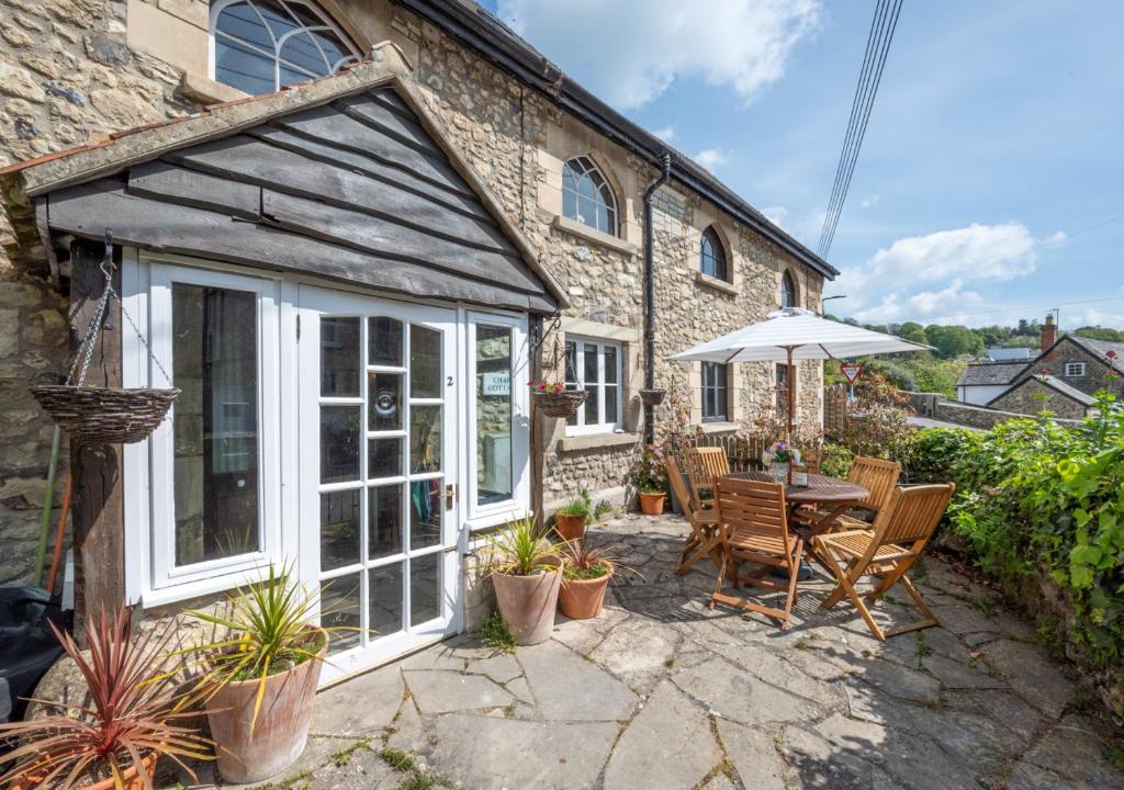a stone house with a patio with a table and chairs at Chart Cottage in Beer