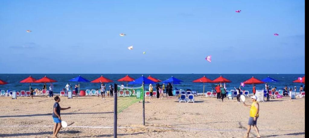 eine Gruppe von Menschen an einem Strand, die Drachen fliegen in der Unterkunft Porto Said Tourist Resort Luxury Hotel Apartment in Port Said