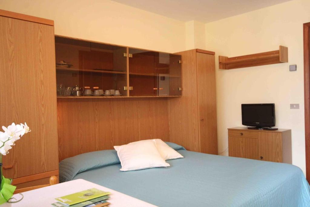 een slaapkamer met een blauw bed en een televisie bij Monolocale a due passi dal cuore di Saint-Vincent in Saint Vincent