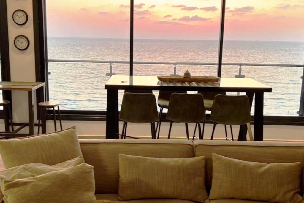 a living room with a couch and a table and the ocean at The Kingdom On The Beach in Bat Yam