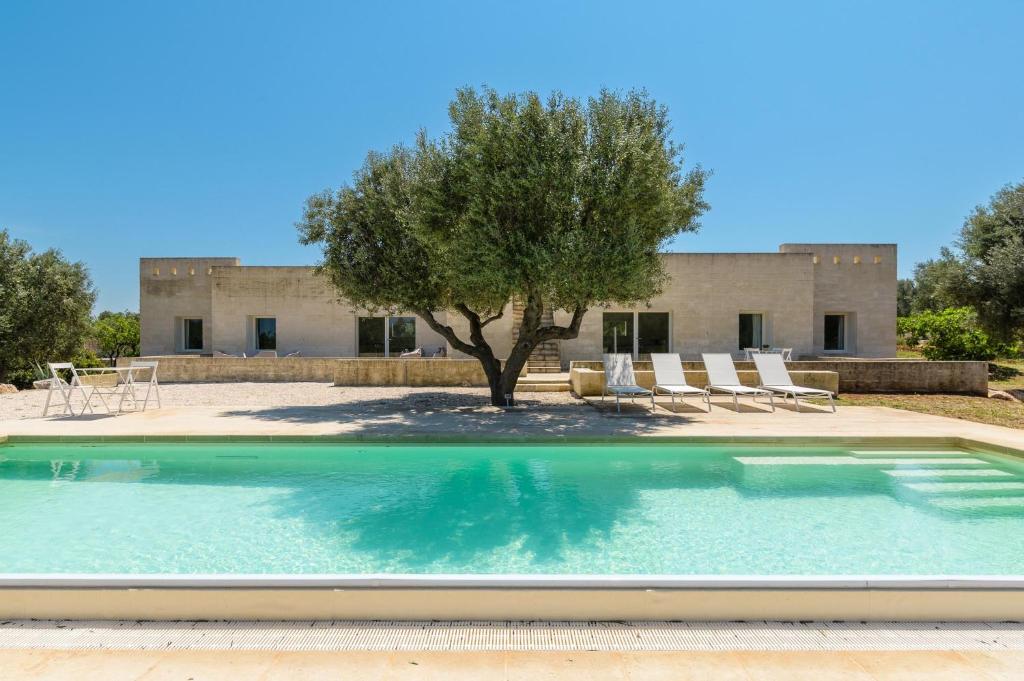 uma piscina em frente a um edifício com uma árvore em Villa La Guaceta by Wonderful Italy em Carovigno