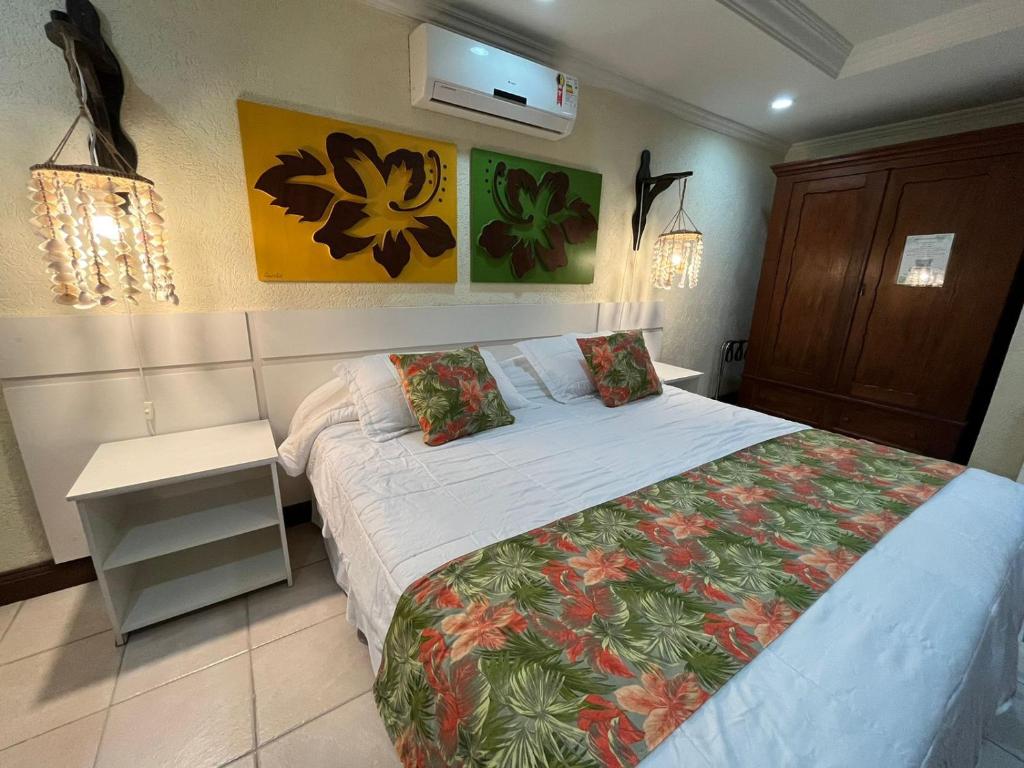 a bedroom with a large bed with a white bedspread and avertisement at Pousada Kaloa Eco Village in Bombinhas