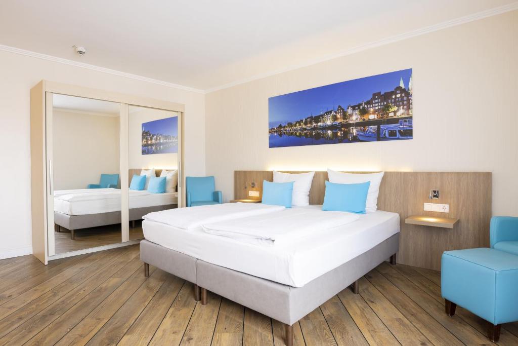 ein Hotelzimmer mit einem Bett und einem Spiegel in der Unterkunft Hotel Vier Jahreszeiten Lübeck in Lübeck