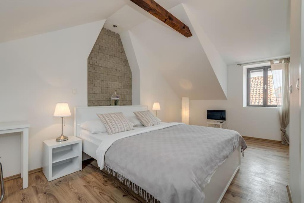 a white bedroom with a bed and a brick wall at 3 bedrooms charming stone house in old town in Trogir