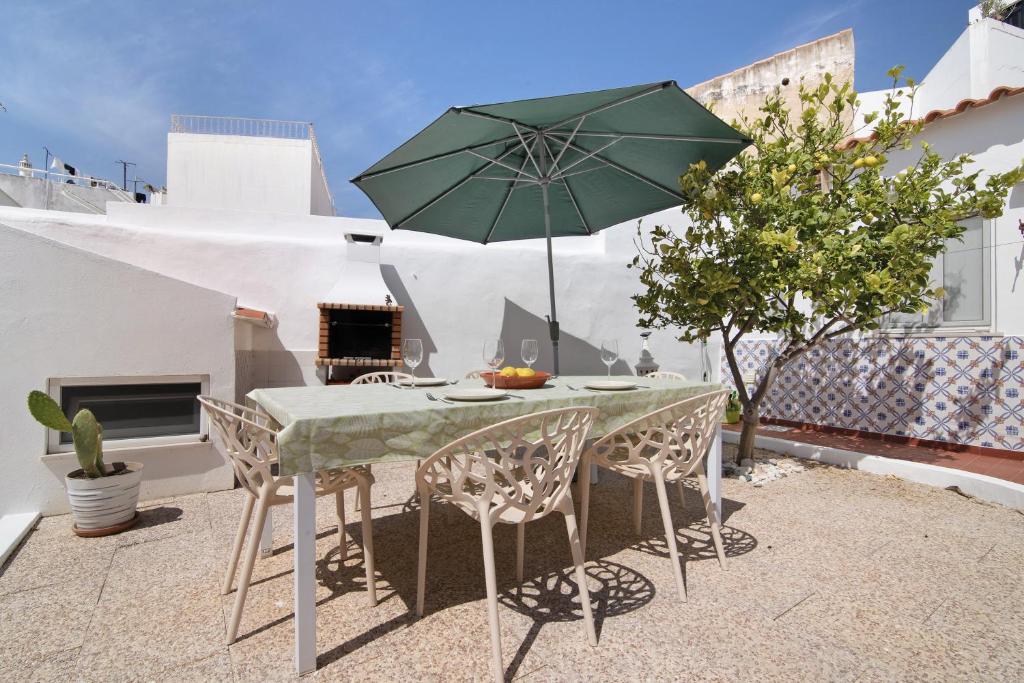 un tavolo e sedie con un ombrellone in un patio di Casa Limoeiro ad Albufeira