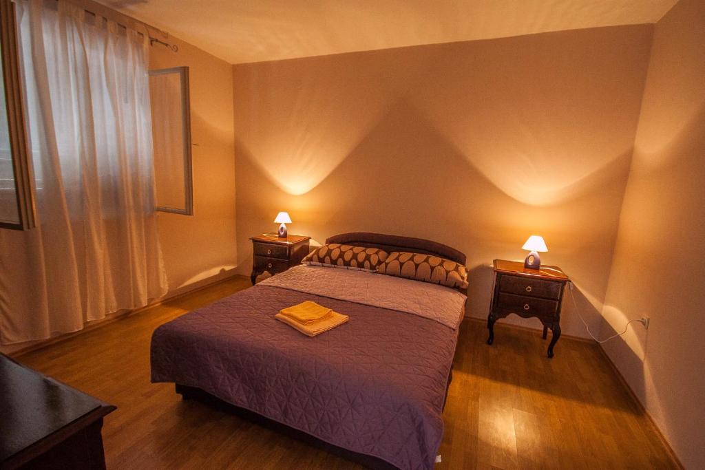 um quarto com uma cama e duas mesas de cabeceira com candeeiros em Apartments Nela em Zadar