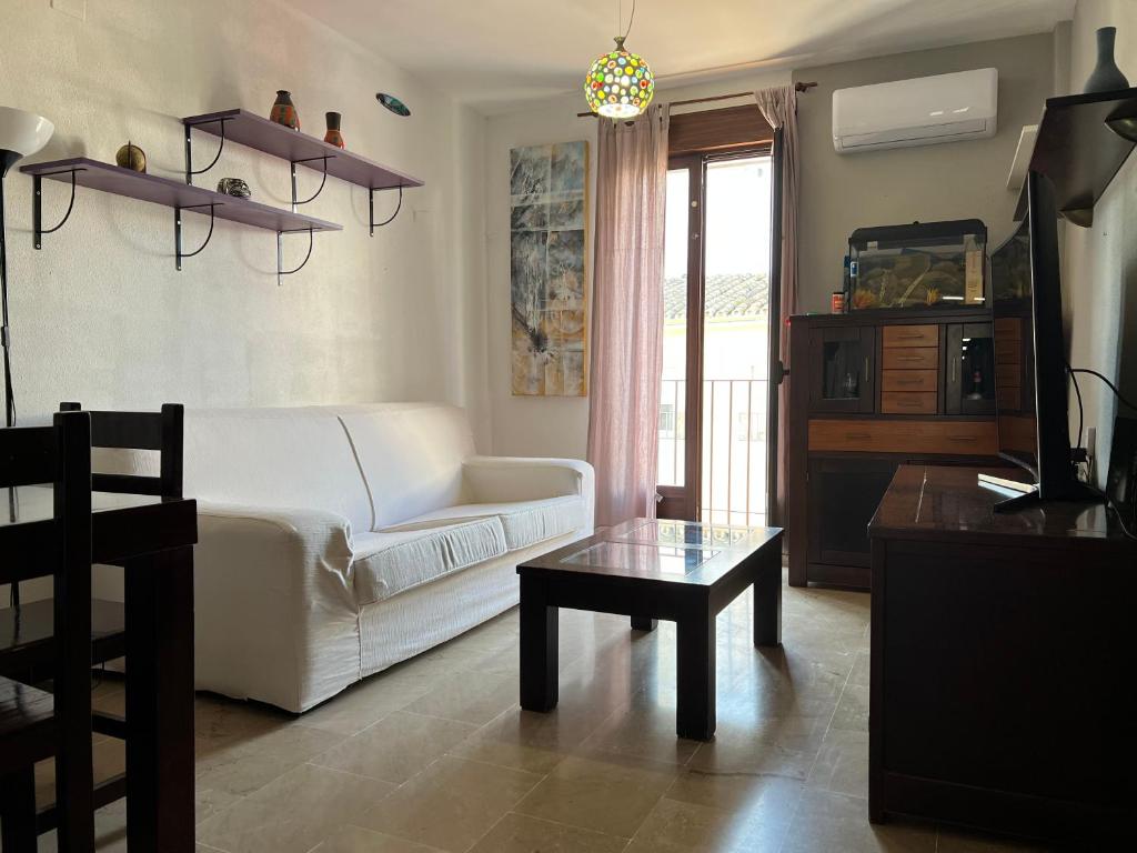 Huerto Apartment في لوسينا: غرفة معيشة مع أريكة بيضاء وطاولة