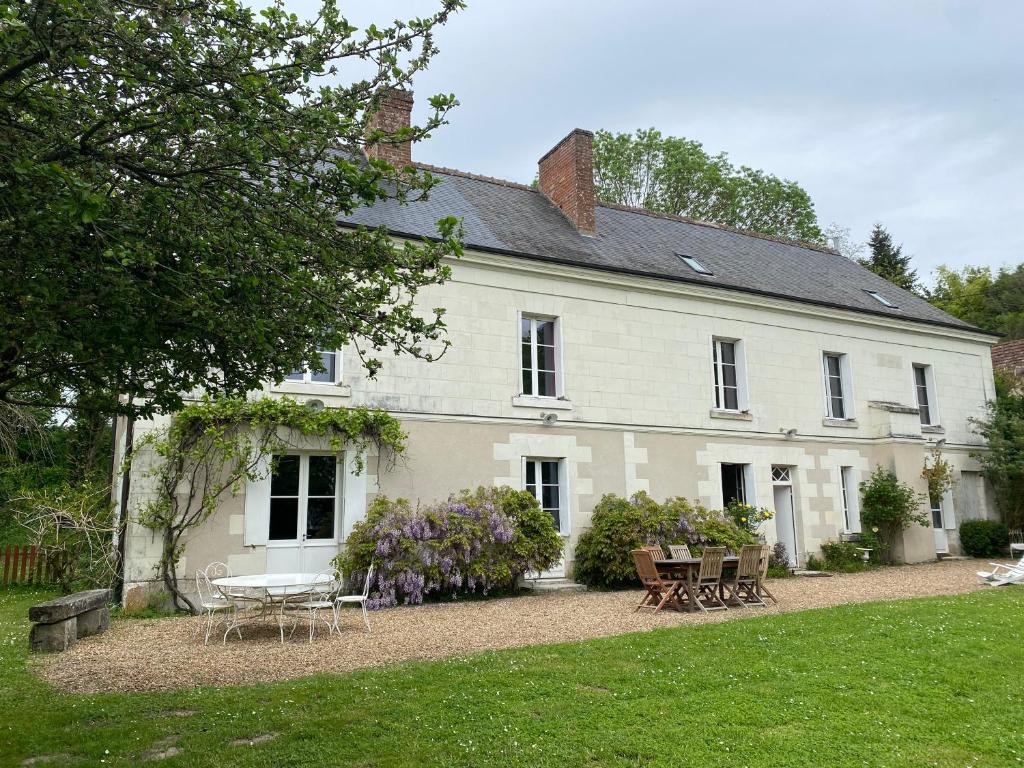 une maison blanche avec des tables et des chaises dans la cour dans l'établissement Moulin de Battereau - Jardin & Verger - 9km d'Amboise, à Saint-Martin-le-Beau