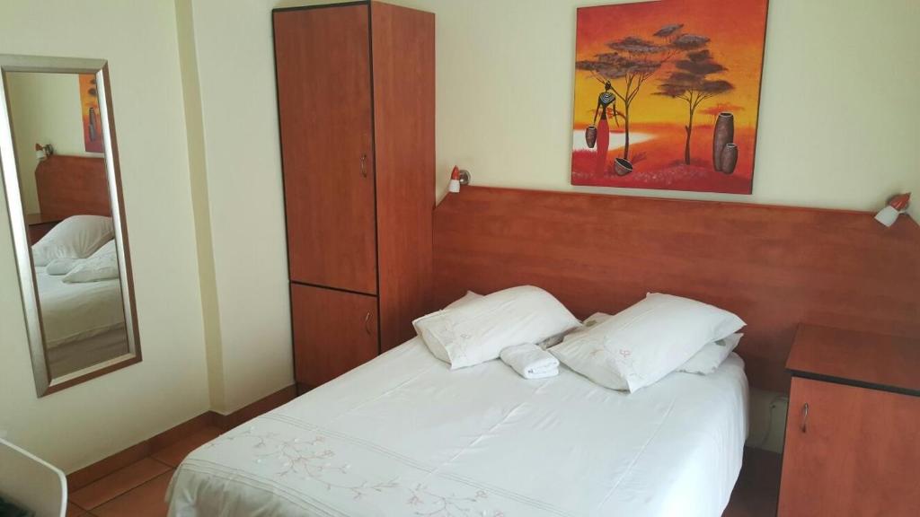 ウィットバンクにあるDeletz Guesthouseの白いベッドと鏡のある寝室