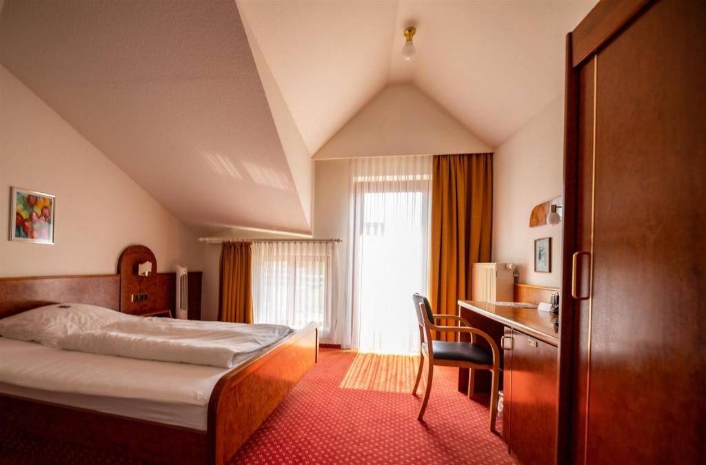 a hotel room with a bed and a desk at Hotel Post Viernheim UG in Viernheim