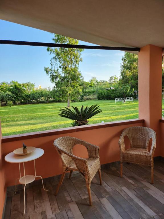 une terrasse avec des chaises, une table et une grande fenêtre. dans l'établissement Aristea Case Vacanza, à Cirella