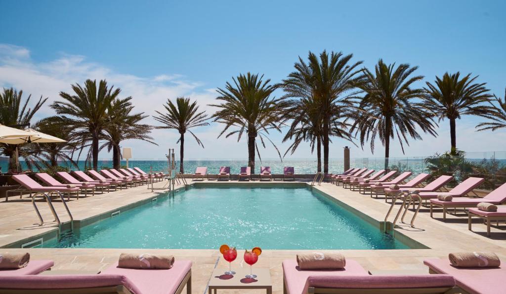 a swimming pool with chairs and palm trees at Pure Salt Garonda - Adults Only in Playa de Palma