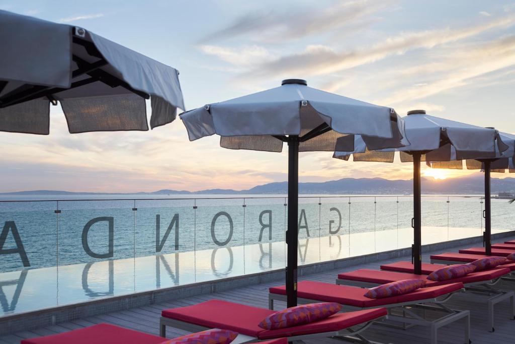 a row of lounge chairs with umbrellas and the ocean at Pure Salt Garonda - Adults Only in Playa de Palma