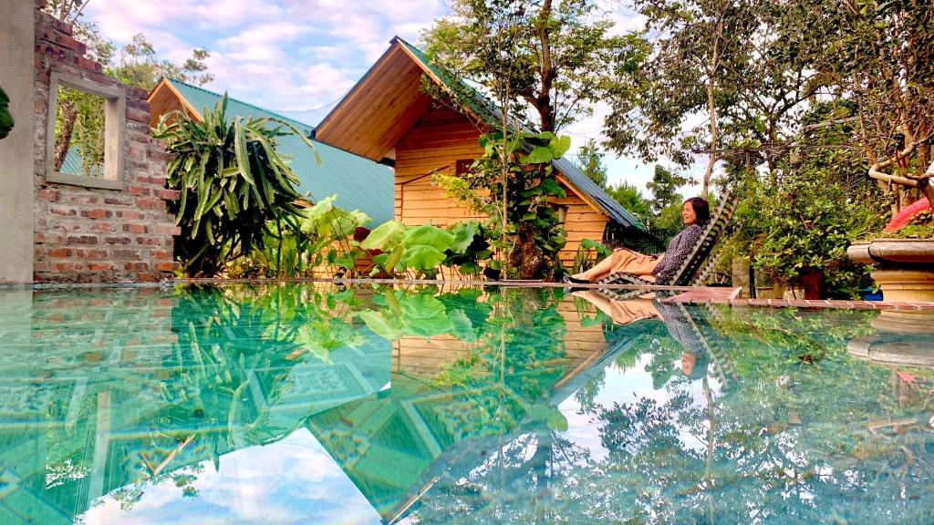 uma pessoa sentada ao lado de uma piscina ao lado de uma casa em Nobita Homestay bắc hà em Bắc Hà
