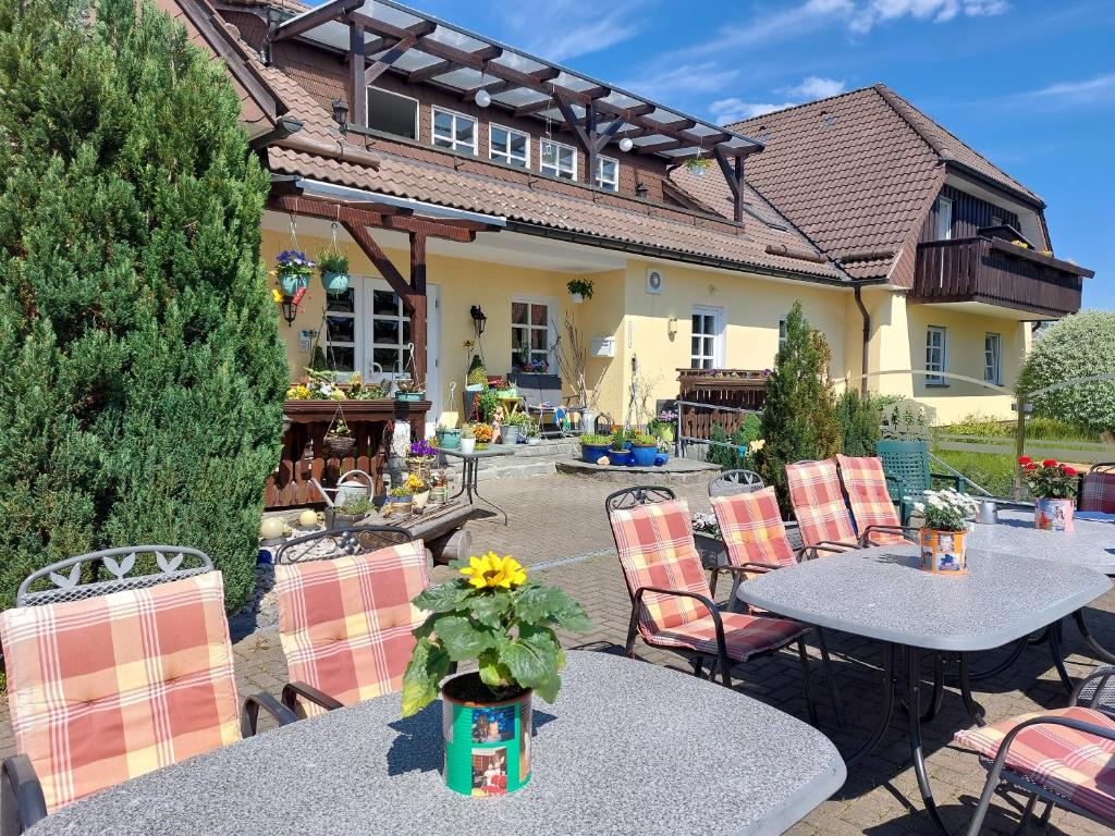 eine Terrasse mit Tischen und Stühlen und ein Haus in der Unterkunft Hotel Zum Poppschen Gut in Olbernhau