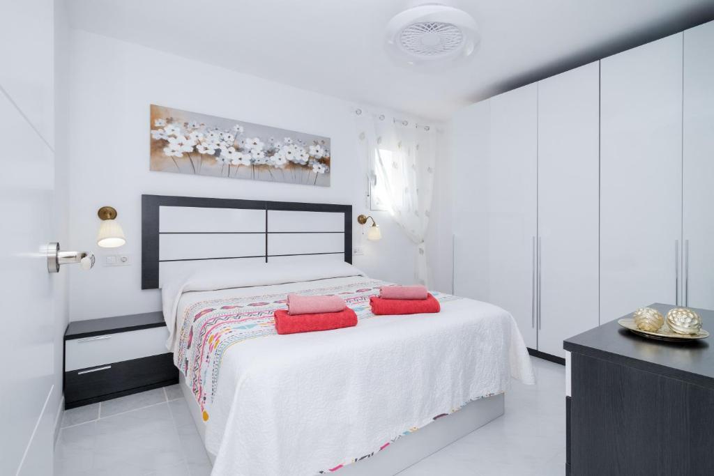 a white bedroom with a bed with red pillows on it at La Mata Londres 2 in La Mata