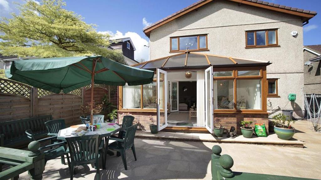 a patio with a table and an umbrella in front of a house at Garrod Avenue in Dunvant