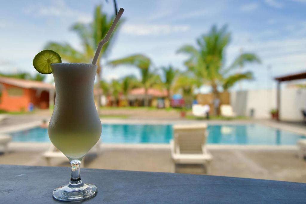 a drink with a lime on a table next to a pool at ÓRGANOS BEACH bungalows & suites in Los Órganos