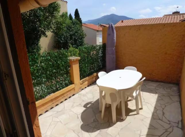 un patio avec une table et des chaises blanches sur un balcon dans l'établissement LECOSY, au Boulou