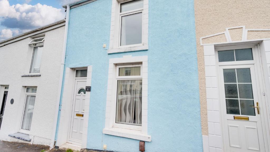 ein blaues Haus mit weißen Türen auf einer Straße in der Unterkunft Delfryn Cottage in The Mumbles