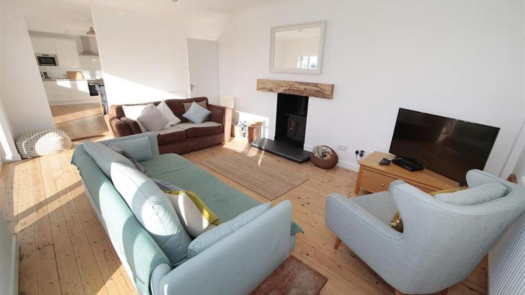 a living room with a couch and two chairs and a television at Rhossili Reach in Rhossili
