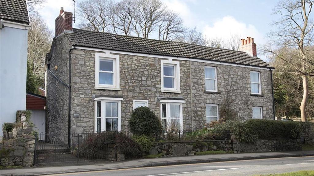 a brick house with white windows on a street at Daisy Cottage in The Mumbles