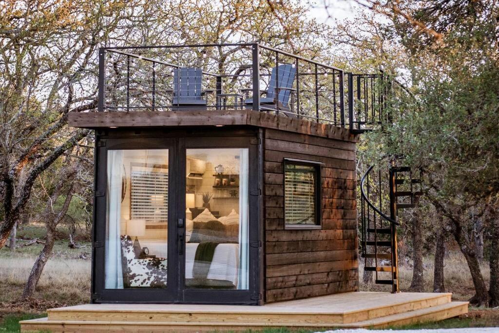 a tiny house with a balcony on top of it at New The Lone Star Shipping Container in Fredericksburg