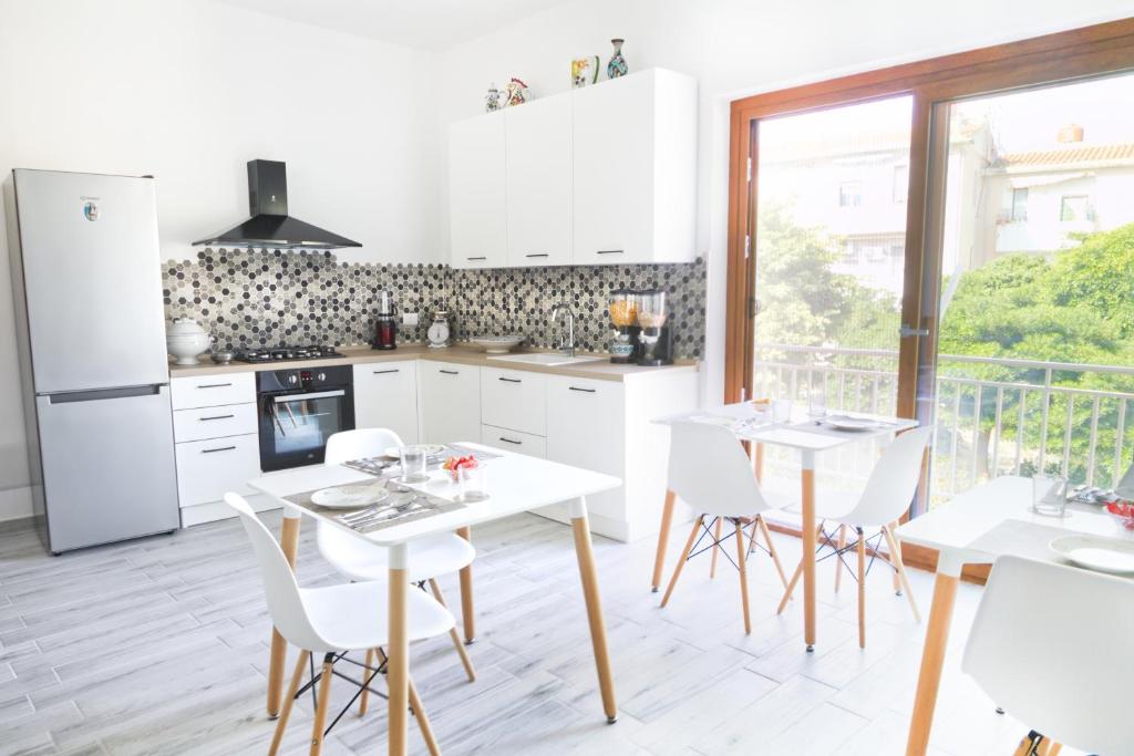 uma cozinha com armários brancos e mesas e cadeiras brancas em Mencin em Carloforte
