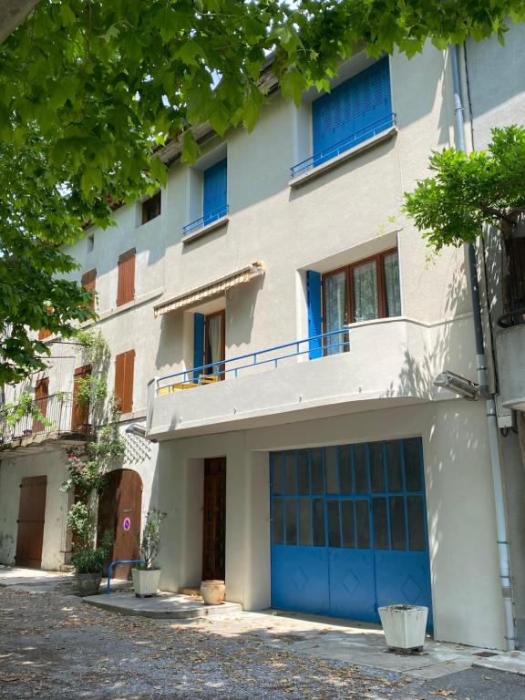 an apartment building with blue garage doors and trees at NOUVEAU Maison de la place in Jaujac