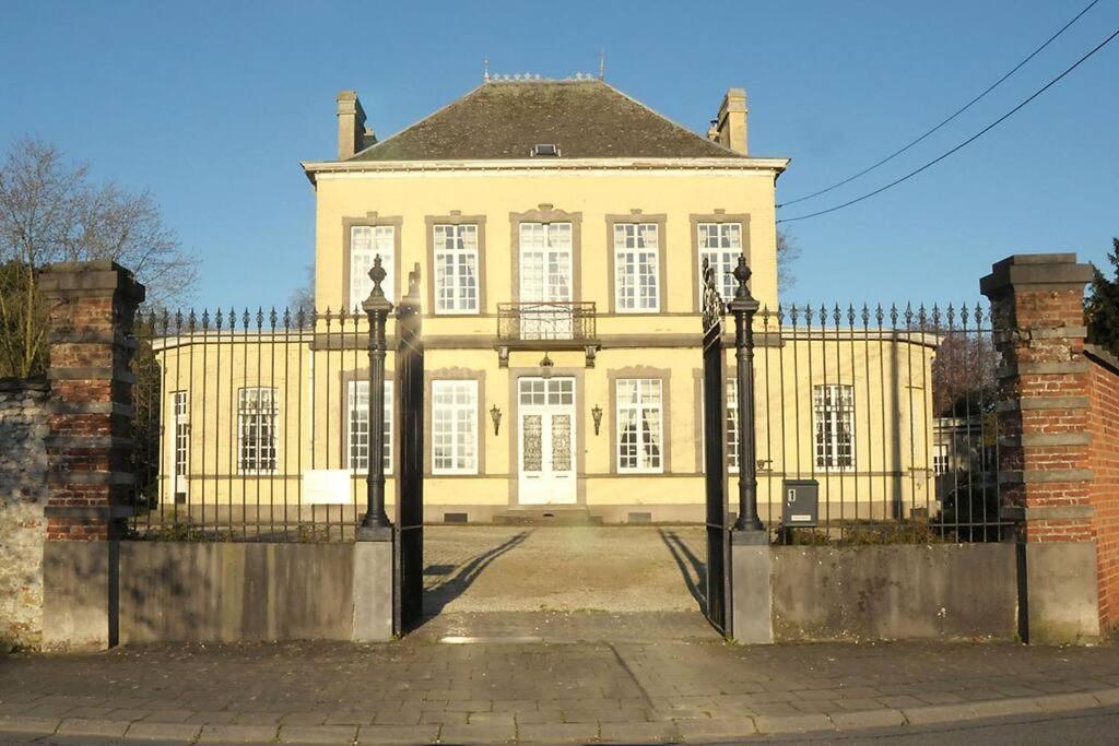 una gran casa amarilla con una valla delante en Petit château à la campagne., en Beloeil