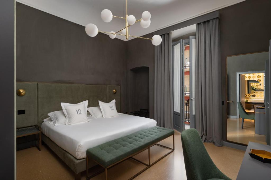 a bedroom with a white bed and a green bench at VIS Urban Suites&Spa in Bari
