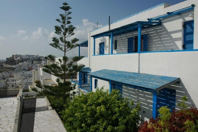 een blauw-wit gebouw met een boom ervoor bij Pension Ocean View in Naxos Chora