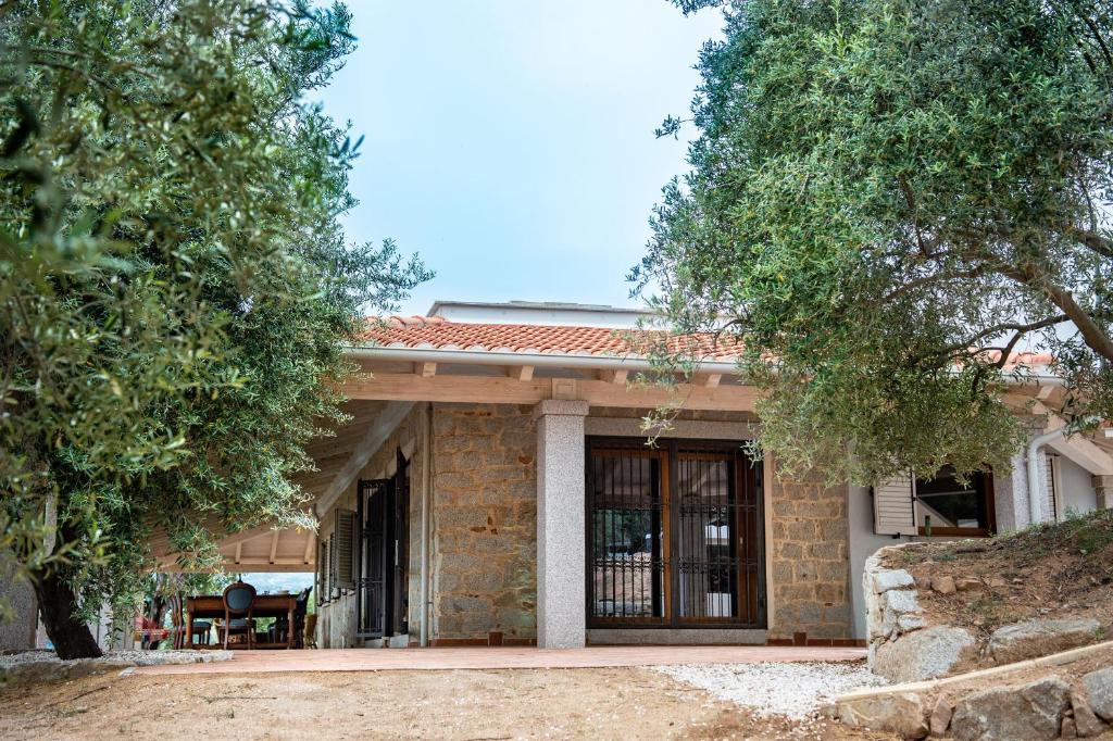 una pequeña casa de ladrillo con porche y árboles en Villa S'Olioni en Loceri