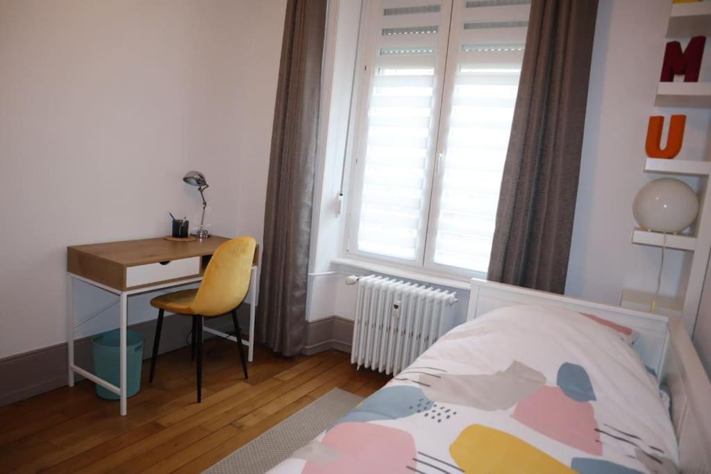 a bedroom with a bed and a desk and a window at Le petit Gambetta in Belfort