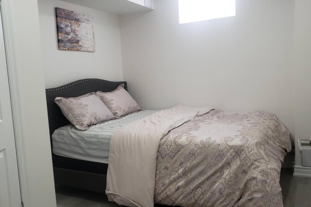 a small bedroom with a bed with a comforter and pillows at An Ideal Apartment for you. in Brampton