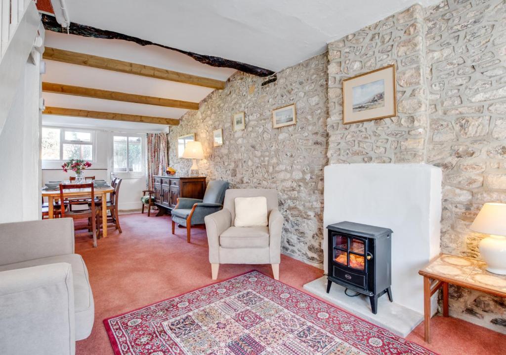 a living room with a stone wall and a wood stove at The Malt House in Colyton